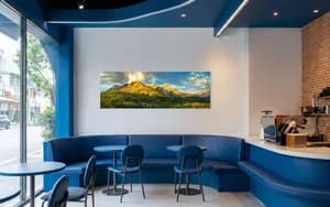 Panoramic fine art print of golden autumn mountain peaks mounted on a modern blue cafe wall.