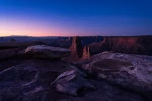 Blue hour landscape photograph of a dramatic Utah desert canyon with sandstone cliffs beneath a star-filled twilight sky.