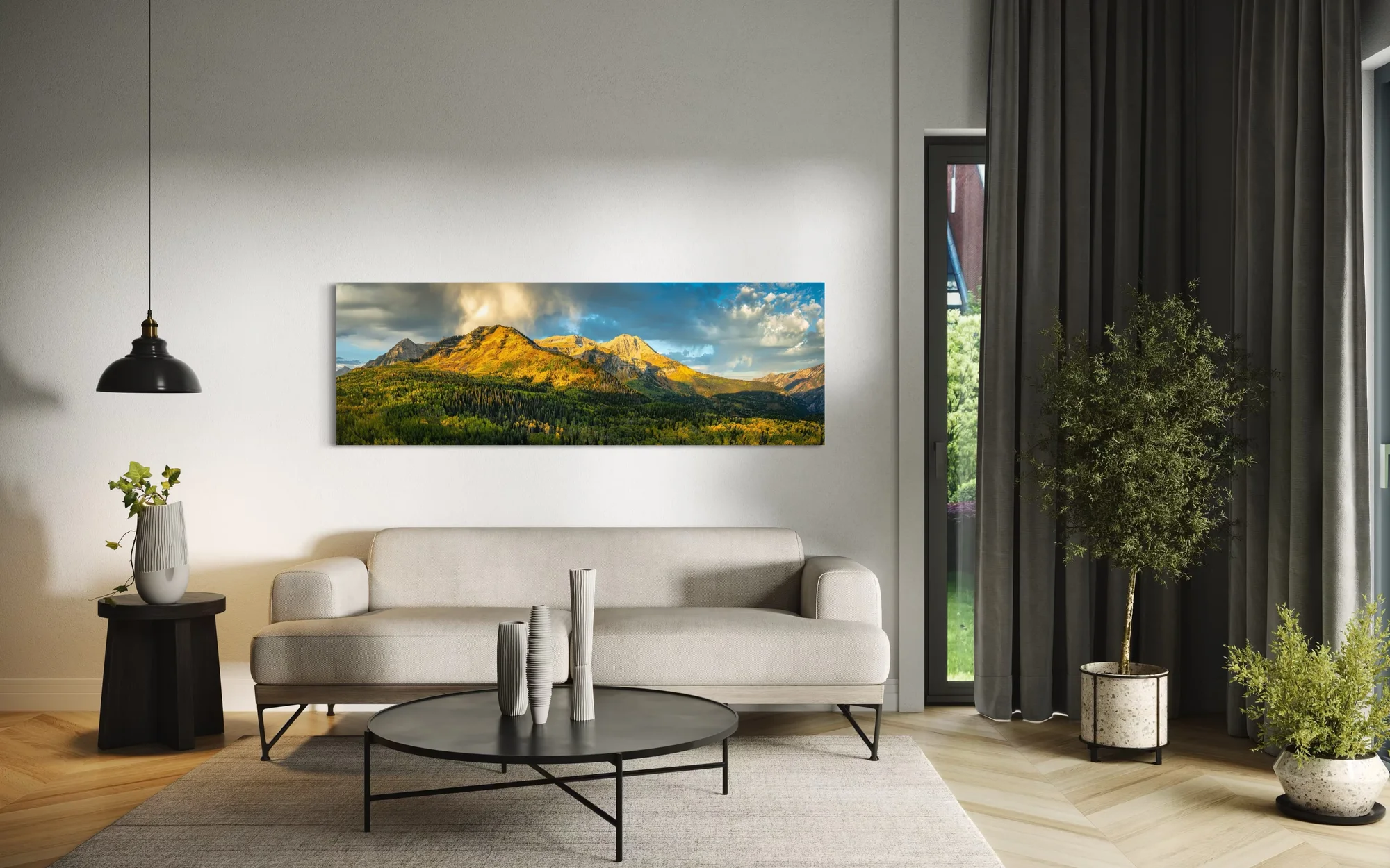 Panoramic fine art print of sunlit mountain peaks framed by golden autumn aspens displayed above a sofa in a modern interior.