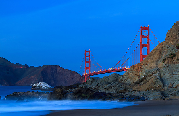 The Golden Gate Bridge in San Francisco as viewed from Marshall Beach as the night slowly makes its way in as the evening waves crash over the rocks on the beach (Clint Losee)